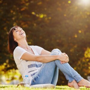 Happy woman sitting outside barefoot