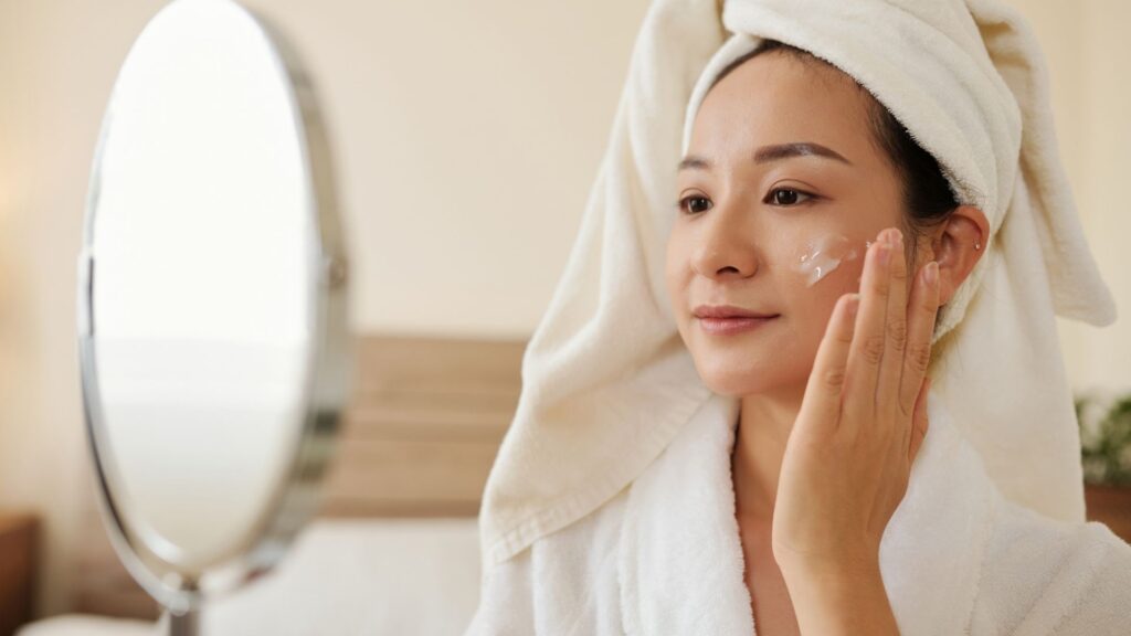 woman looking in the mirror and putting on face cream