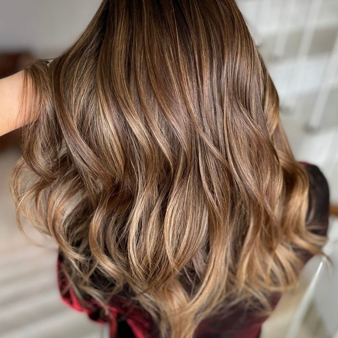 hair stylist running her hand through client's long wavy hair after at a solon visit